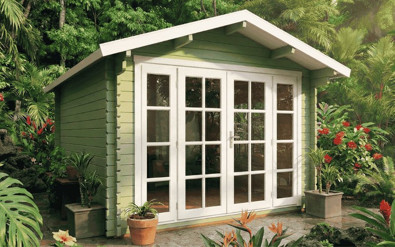 Classic green wood cabin shed surrounded by tropical plants